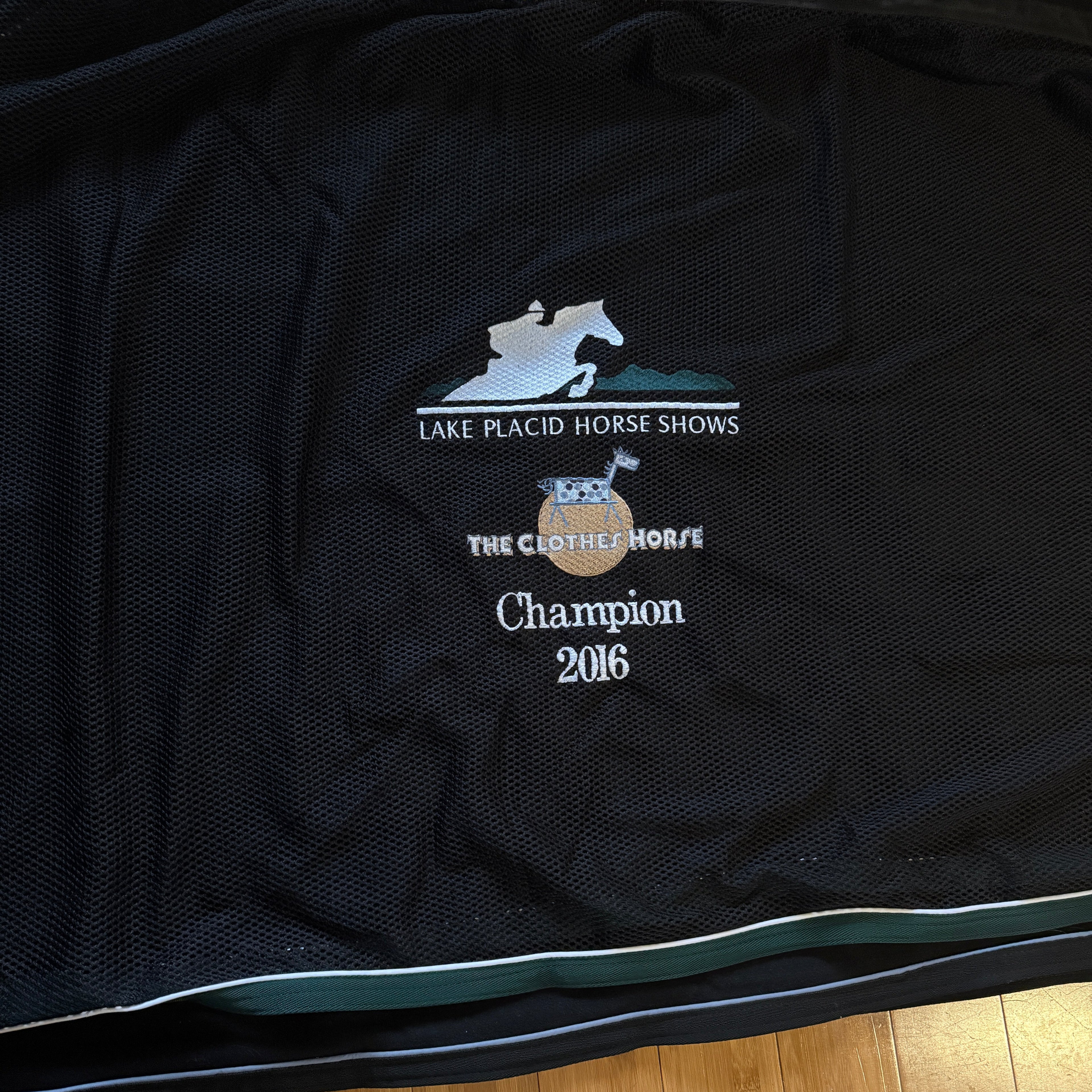 Black horse scrim with embroidered text.